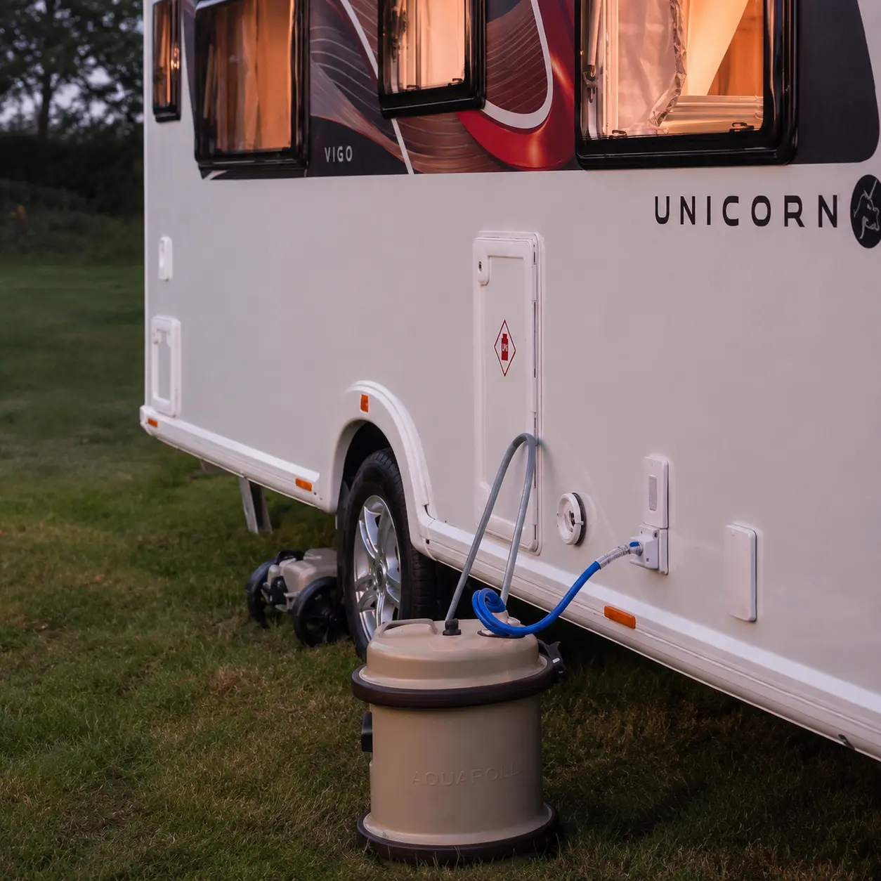Aquaroll water container and caravan water pump setup beside a touring caravan
